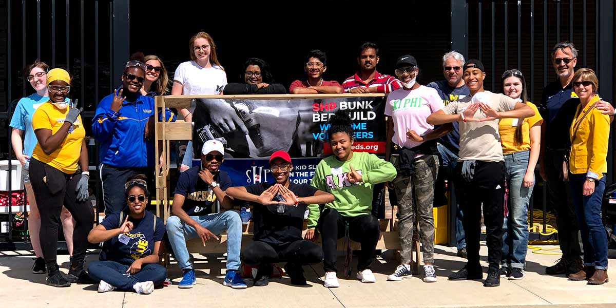 group of volunteers standing in front of bunk beds that they built