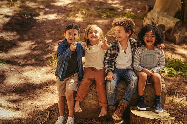 kids sitting on a log outdoors in the woods