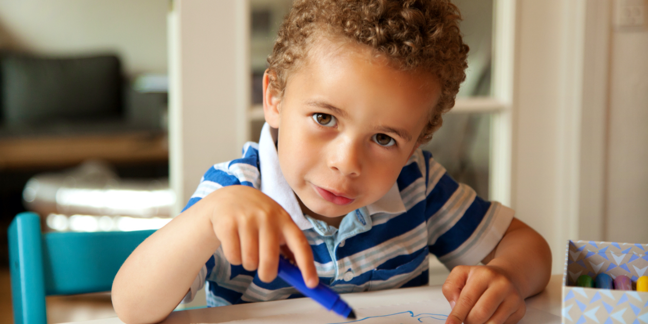 photo of little boy holding a blue crayon