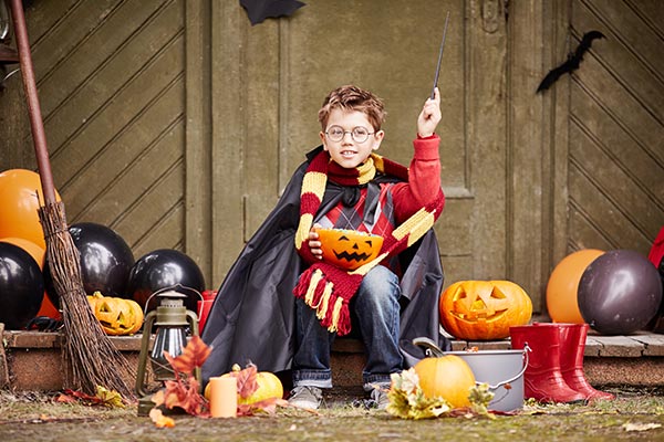 boy in halloween costume holding a pumpkin candy bowl