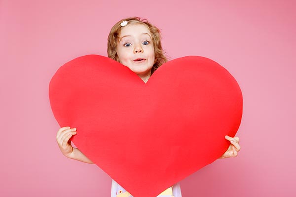 young girl holding a large heart